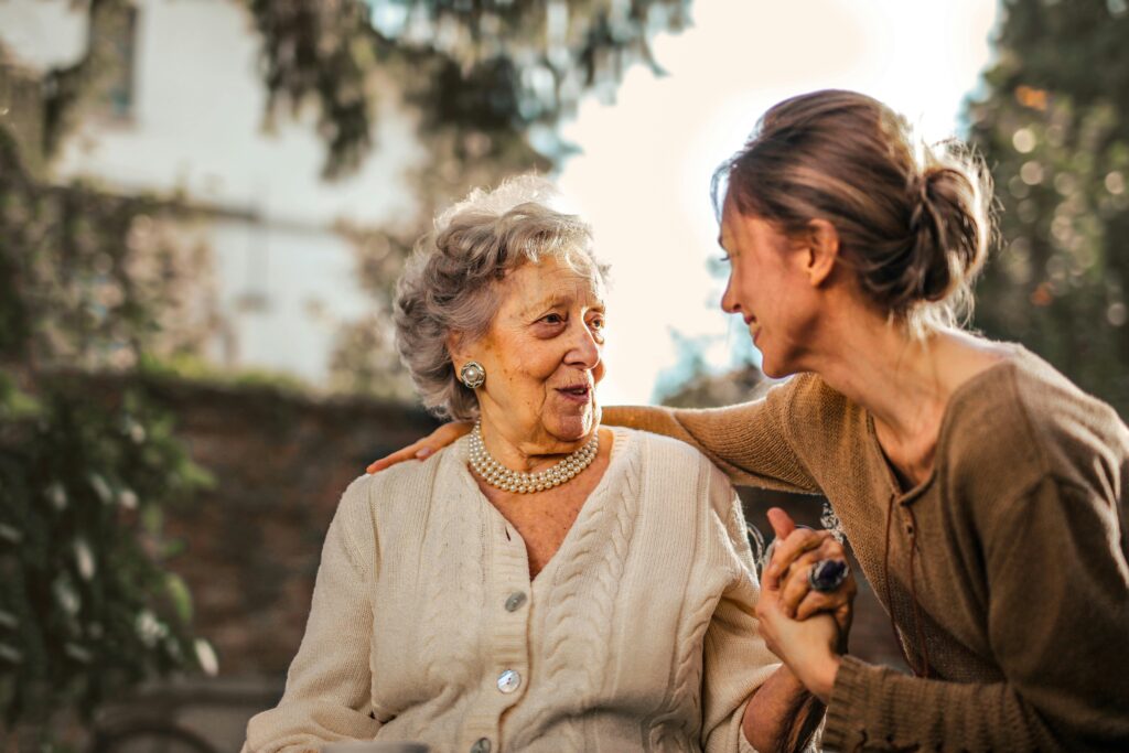 Younger woman holding the hand of an older Woman who is smiling at her